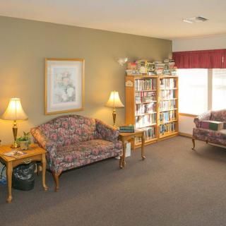 A cozy living room with a sofa, bookshelf, and lamps.