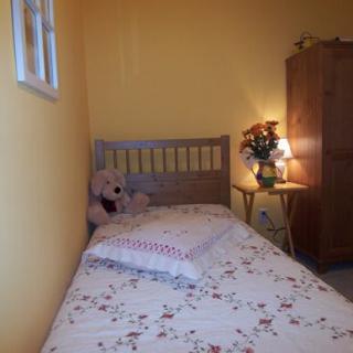 A cozy bedroom with a single bed, floral bedding, and a teddy bear.