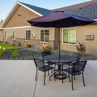 A patio with outdoor furniture and an umbrella in front of a building.
