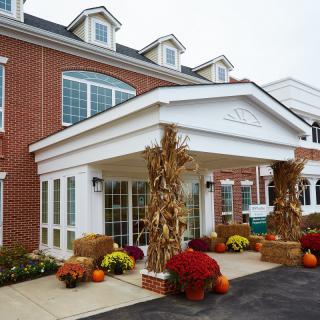 A building with autumn decorations featuring pumpkins, hay bales, and flowers at the entrance.