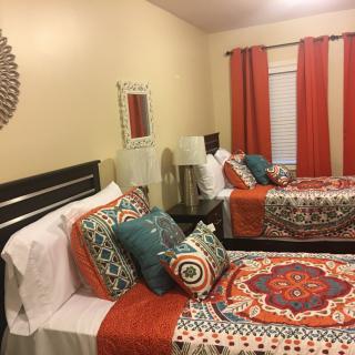A cozy bedroom with two twin beds featuring colorful bedding and decorative pillows.