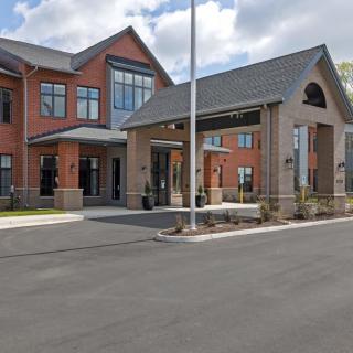 A modern brick building with a covered entrance and driveway under a cloudy sky.