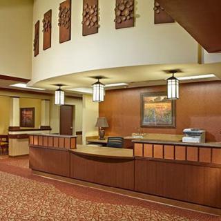 A spacious hotel lobby reception area with modern decor and warm lighting.
