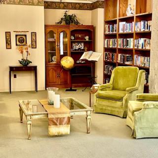 A cozy living room with bookshelves, armchairs, and a globe.