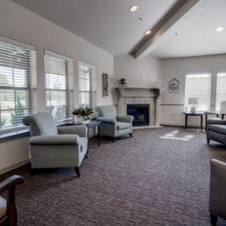A cozy living room with ample seating, large windows, and a fireplace.
