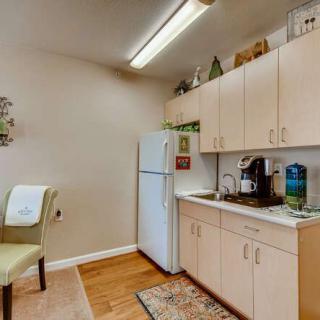 A cozy kitchen area with light wooden cabinets, a refrigerator, and a coffee machine.