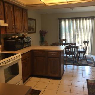 A kitchen with wood cabinets leads into a dining area with a table and chairs.