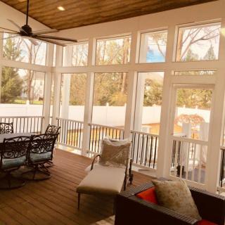 A cozy sunroom with large windows, wooden floors, and comfortable seating.
