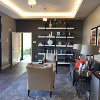 A modern living room with armchairs, shelves filled with books and vases, complemented by stylish lamps.
