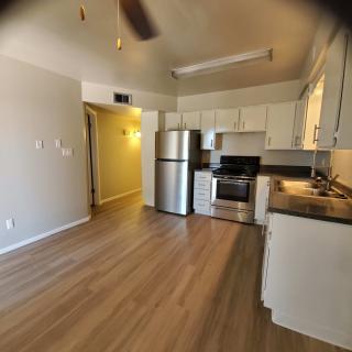 A modern apartment kitchen with stainless steel appliances and wooden flooring.