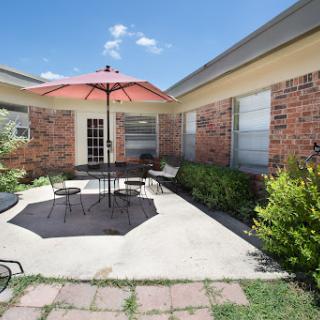 A cozy outdoor patio area featuring a bright umbrella and seating for relaxation.