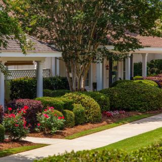 A beautifully landscaped house with a well-maintained garden and a neat sidewalk.