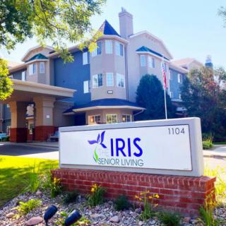 A welcoming entrance of the Iris Senior Living facility, showcasing its prominent signage and surrounding landscape.