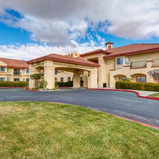 A well-maintained hotel exterior with a driveway and a cloudy sky backdrop.