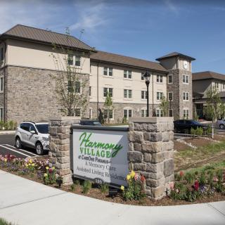 A modern apartment complex with a landscaped entrance and parking area.