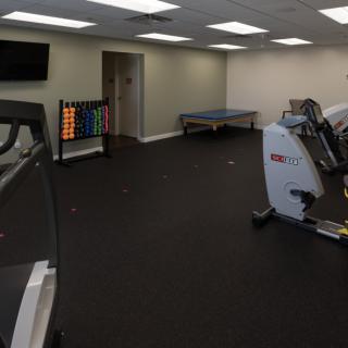 A gym room with exercise equipment including treadmills, stationary bikes, and weights.