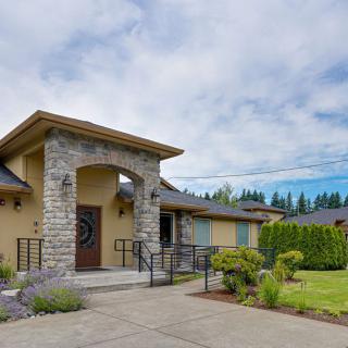 A modern house with a stone entrance and well-maintained front yard under a cloudy sky.