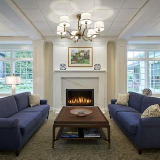 A cozy living room featuring blue sofas, a warm fireplace, and elegant lighting.