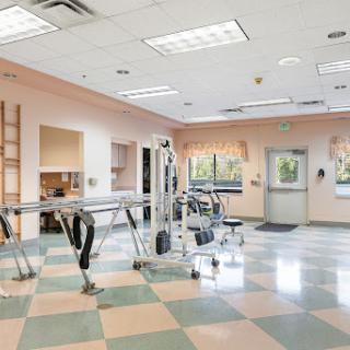 A spacious rehabilitation room equipped with exercise equipment, designed for physical therapy sessions.