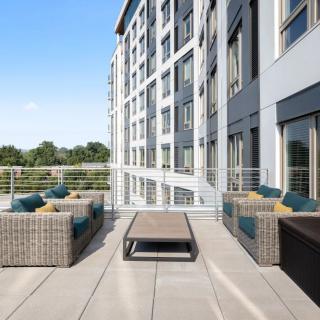 A modern apartment building with a spacious outdoor patio featuring stylish wicker furniture.