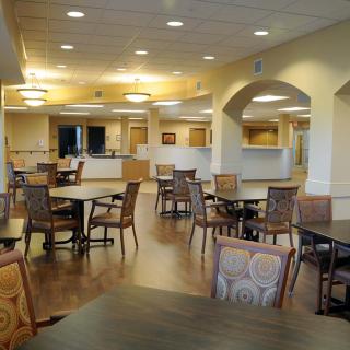 A spacious and well-lit dining area featuring multiple tables and chairs arranged for guests.