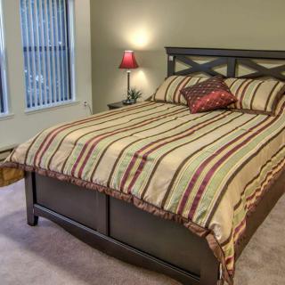 A cozy bedroom with a striped bedspread and a red pillow.