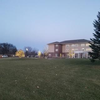 A serene view of a building surrounded by grass and trees during the evening.