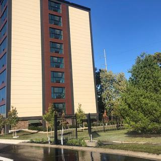 A modern office building surrounded by trees under a clear blue sky.