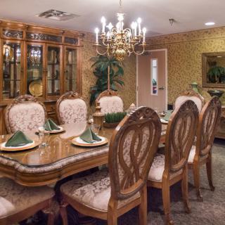 An elegant dining room with a chandelier and traditional wooden furniture, set for a meal.