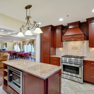A modern luxury kitchen with wooden cabinets, a central island, and stainless steel appliances.