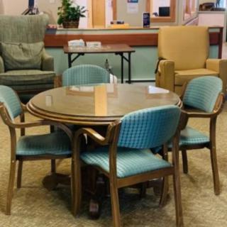 A cozy indoor seating area featuring a table surrounded by blue cushioned chairs and armchairs.