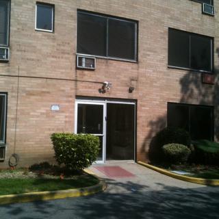 The image shows the entrance of a brick building with surrounding landscaping.