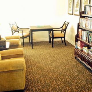 A cozy living room with a table, chairs, and a well-stocked bookshelf.