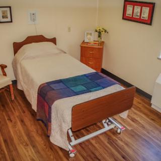 A cozy hospital room featuring a single bed and bedside furniture.