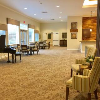 A cozy lounge area featuring a piano, seating arrangements, and large windows.