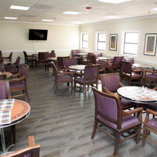 A spacious dining area with multiple tables and chairs, featuring a television on the wall.