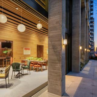 A modern restaurant with an inviting outdoor patio area, illuminated by warm lighting in an urban setting during the evening.