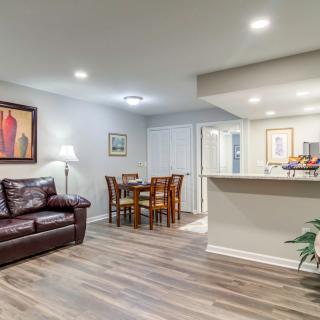 A modern living room with a cozy seating area and adjacent dining table, featuring stylish decor and wooden flooring.