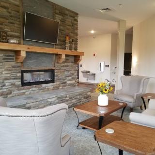 A modern living room with a stone fireplace and mounted television, featuring cozy seating and contemporary decor.