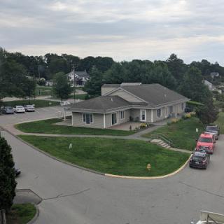 A view of a building situated in a peaceful residential neighborhood with a cloudy sky overhead.