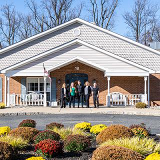 A group of people standing in front of a building surrounded by landscaped gardens.