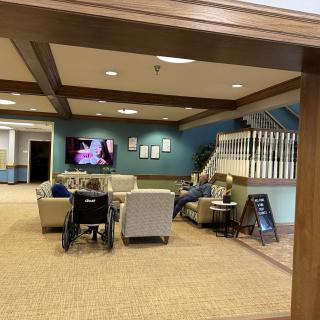 A cozy lounge area with comfortable seating, a television, and a staircase in the background.