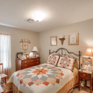 A cozy, traditionally decorated bedroom featuring a quilt-covered bed and wooden furniture.