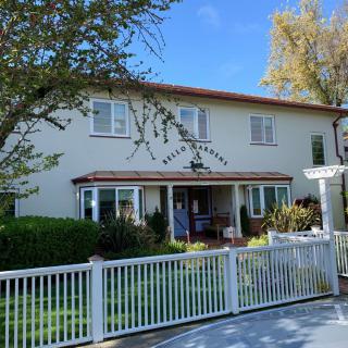 A charming two-story house with a white fence and a well-maintained garden.