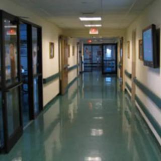A quiet hospital hallway with reflective flooring and doors on either side.