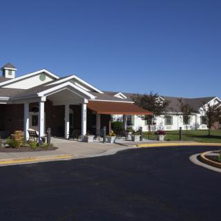 A large building with a covered entrance and driveway under a clear blue sky.