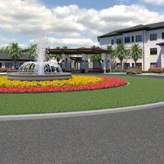 A beautifully landscaped area featuring a fountain and vibrant flower beds in front of a modern building.