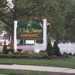 A beautifully landscaped sign for a business, surrounded by trees and flowers.