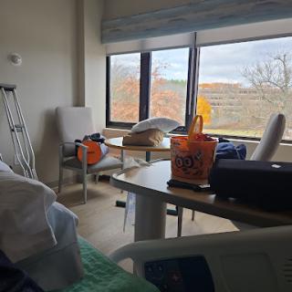 A view of a hospital patient room with natural light streaming through the window, featuring minimal furnishings.