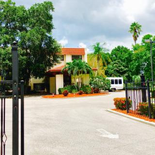 Entrance to a building surrounded by lush greenery and a fenced driveway.